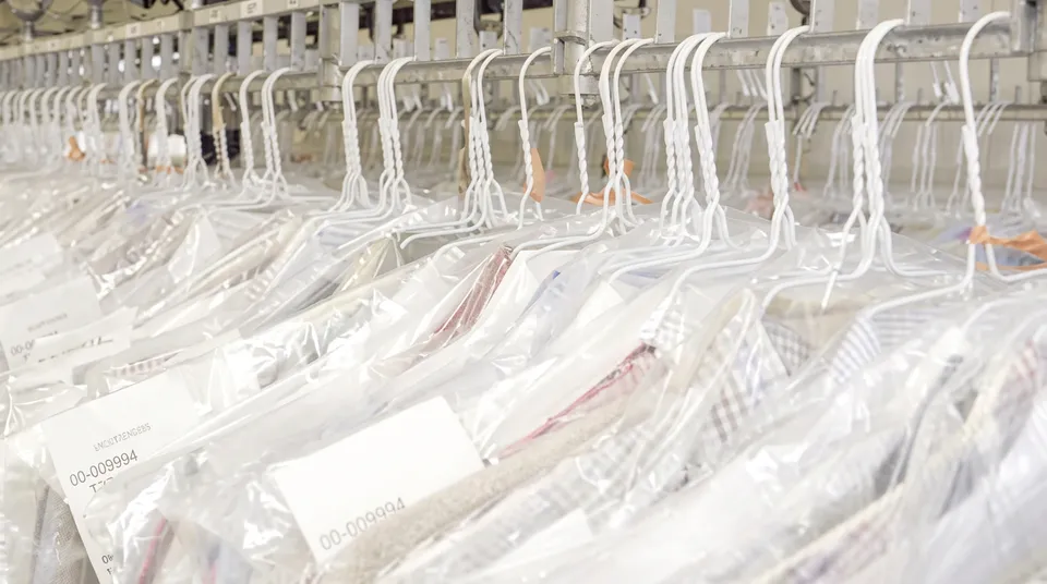 Rows of garments in clear bags hanging on a storage rack